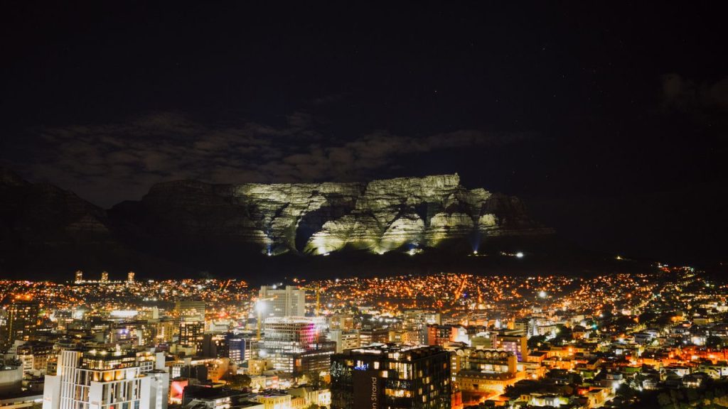 A breathtaking night cityscape of Cape Town, featuring the illuminated Table Mountain as a striking backdrop.
