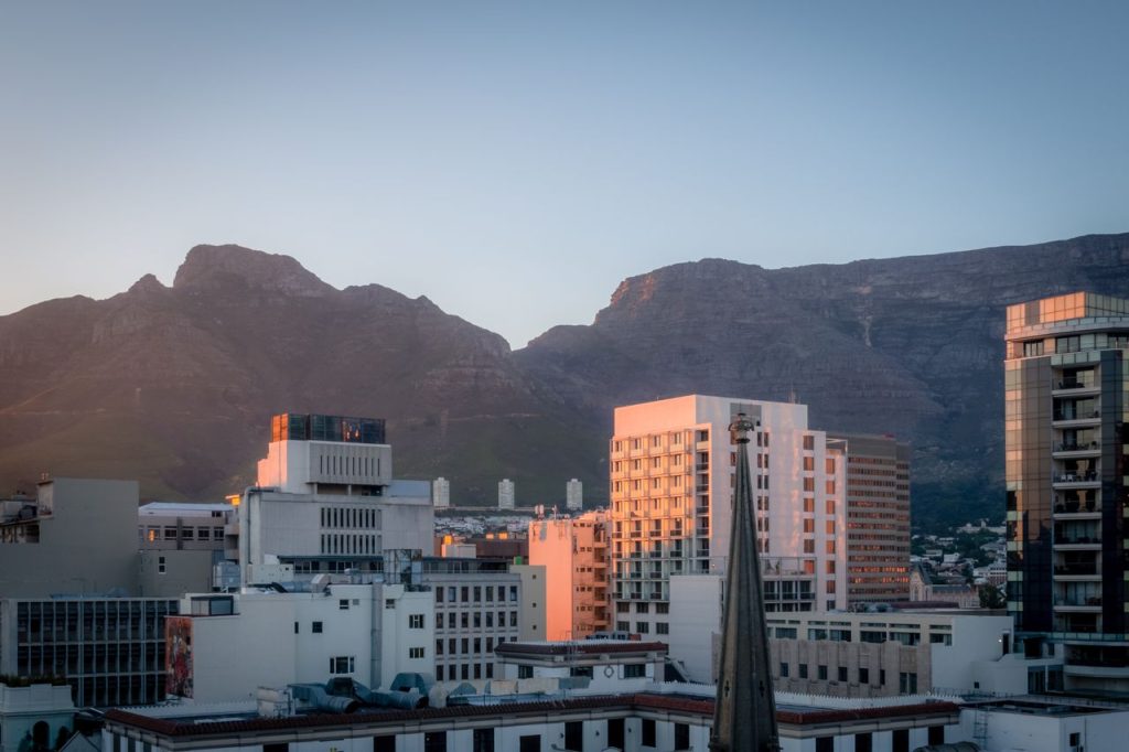 A view of Cape Town cityscape with Table Mountain in the background during sunset.