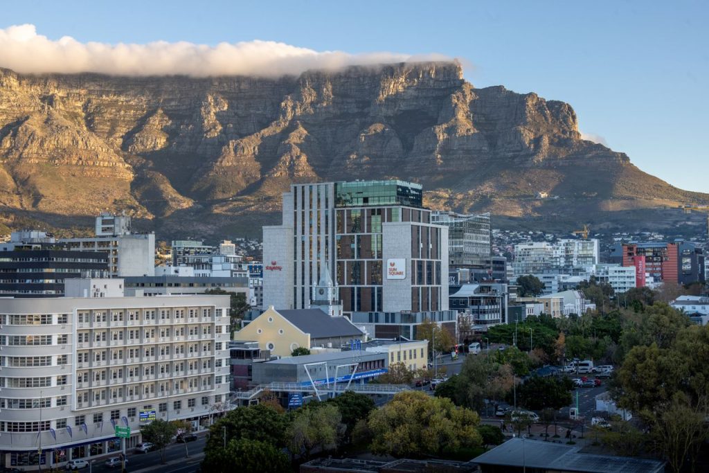 Urban view of Cape Town with Table Mountain at sunrise, capturing the city's architecture.