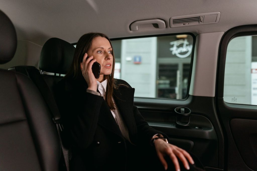 Confident businesswoman talking on phone inside a car. Professional attire, focused expression.